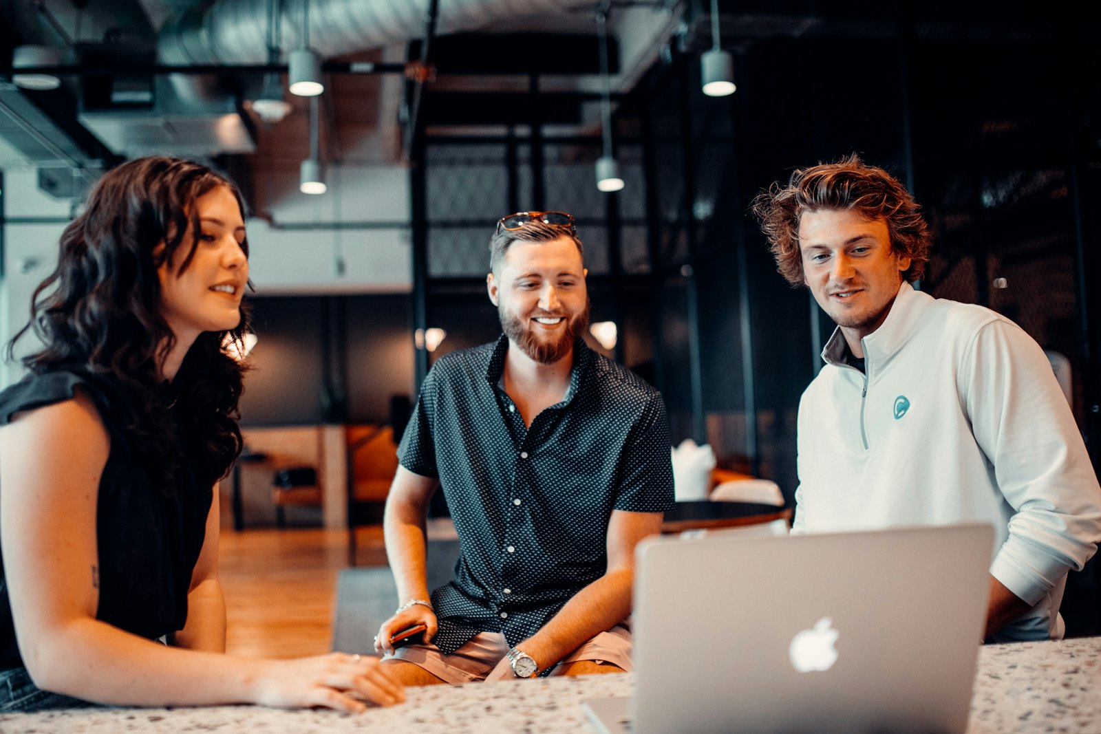 Three colleagues laughing around a laptop
